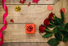 顶部视图，红色礼品盒。节日气氛，红玫瑰花束，缎带和木制背景的蝴蝶结.