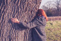 年轻女子在冬季中拥抱一棵大树