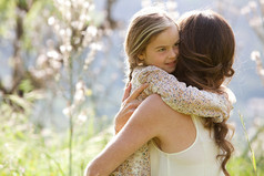 Mother and daughter hugging in a spring field