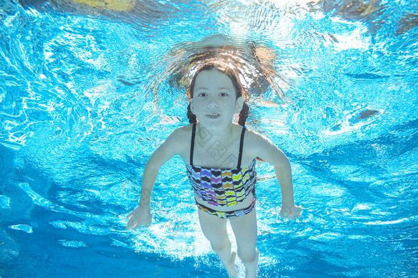 儿童游泳在游泳池水下，快乐积极的女孩已经在水里，孩子运动家庭度假的乐趣