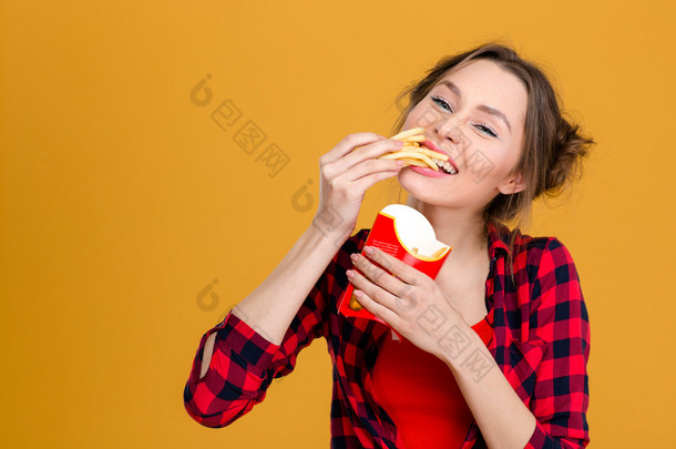 积极年轻的女人穿花格子衬衫，吃薯条