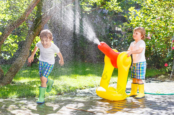 <strong>两个小孩子</strong>玩的橡胶软管和水在夏天