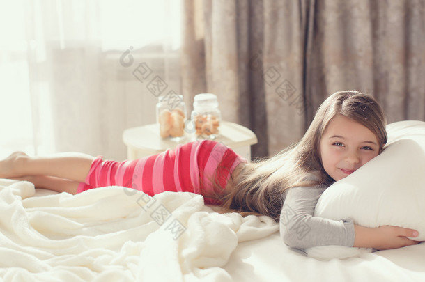 一个小女孩醒来，拥抱枕头的早晨肖像