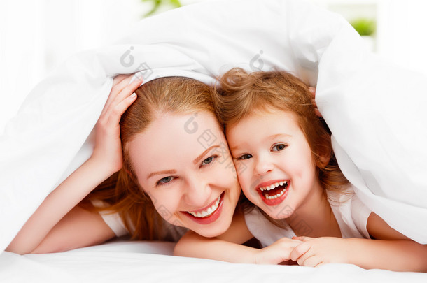 快乐家庭的母亲和孩子玩、 笑<strong>着躺</strong>在床上 