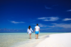 后面的观点的年轻夫妇在白色的沙滩上。度假概念