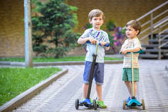 两个可爱的男孩，参加骑滑板车，在公园里，室外夏季.