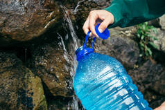 女人的手填满瓶从山区水源