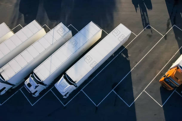 空中顶视图的白色半卡车与货物拖车与其他车辆在专用的停车场停车.