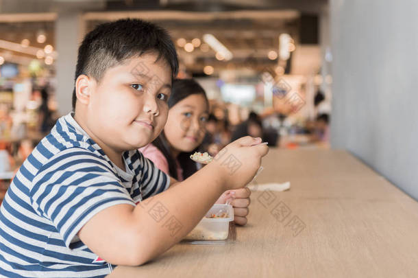 肥胖的弟弟和妹妹在美食广场吃盒饭