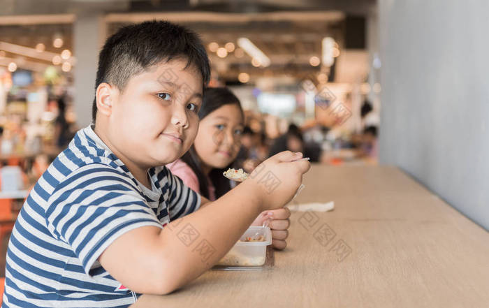 肥胖的弟弟和妹妹在美食广场吃盒饭