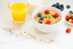 健康早餐在白色石桌背景设置燕麦饼与蓝莓和草莓和黑咖啡、牛奶和橙汁