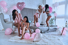愉快的美丽的年轻妇女在睡衣有睡眠党在卧室与气球