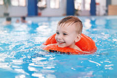 在游泳池里的白种白人孩子的肖像。学龄前男孩的训练, 漂浮在水中的红色圆圈环。健康积极的生活方式