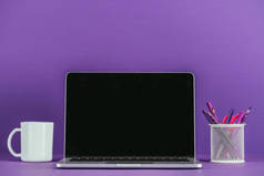 工作场所与笔记本电脑和咖啡杯紫色表面