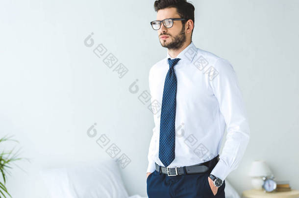 英俊的商人在白色衬衣和领带站立在卧室里