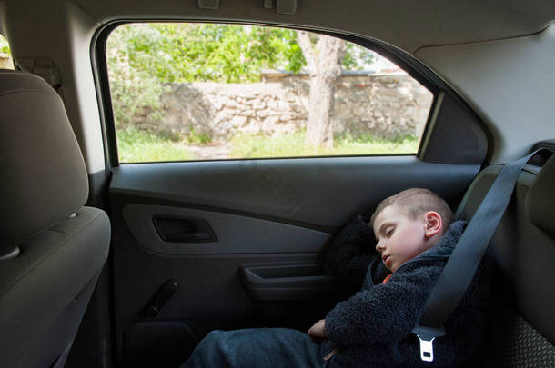 可爱的小男孩睡在车后座上