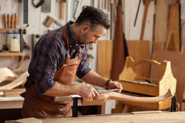 木匠做 Cabriole 腿为古董桌。木匠工作与一个刨床在车间为生产古董家具。他使 cabriole 的腿, 在路易斯 Xv 和安妮女王的风格的表