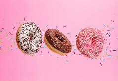 在粉红色的背景下飞行甜甜圈。低重力食品在冷冻运动效果中的概念。高分辨率图像
