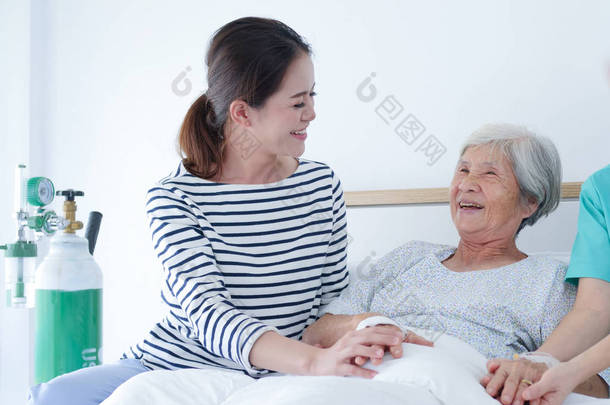 愉快的老年妇女与资深护士和她的女儿谈话在医院房间里