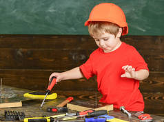 小男孩手持螺丝刀工具。就要手工制作和车间概念。儿童在头盔可爱的发挥建设者或修理工, 或就要手工制作。幼儿在繁忙的脸上玩螺丝刀在车间