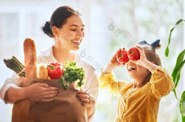 家庭购物。妈妈和她的女儿拿着装有蔬菜的购物袋.