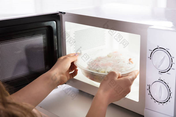 微波烤箱中妇女手加热食品特写