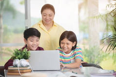 亚洲教师和儿童使用笔记本电脑娱乐.