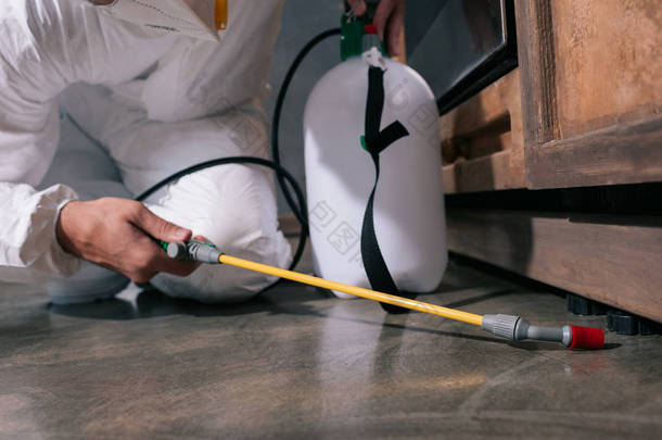 厨房地面害虫防治工作者喷洒杀虫剂的裁剪图像