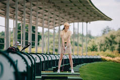 女子在黄色盖帽和马球打高尔夫球在高尔夫球场