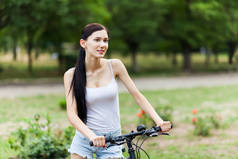 美丽的女孩骑自行车在城市公园。活跃的人。户外