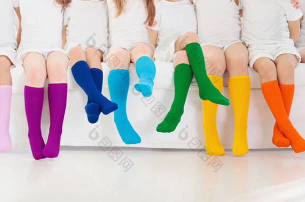 穿着彩色彩虹袜的孩子。<strong>童鞋</strong>系列。各种针织膝盖高袜子和紧身裤.儿童服装和服装。<strong>童装</strong>时尚。男孩和女孩团体的腿和脚.