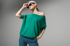 灰色背景下的太阳镜和绿色毛衣造型美女模特 