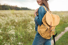 女子用黄色背包站在田野上的镜头