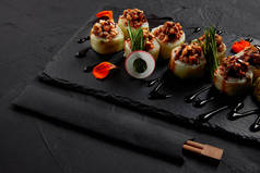 美味寿司卷与奶油鳗鱼和泡菜蛋黄酱在石板板和筷子  