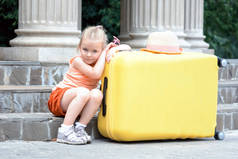 可爱的小女孩与大黄色手提箱户外