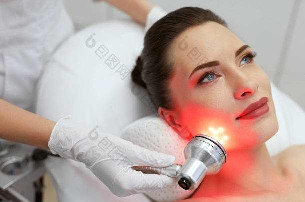 面部美容术。进行红光治疗的妇女 