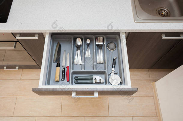 高角度图片清洁白色厨师台面表和打开新的现代木制厨房抽屉用不同的餐具勺, 刀, 叉子和东西