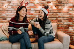 年轻的女孩聊天, 在家里玩得开心。放松庆祝圣诞假期概念。最好的朋友与圣诞老人帽子和鹿欢快的笑声.