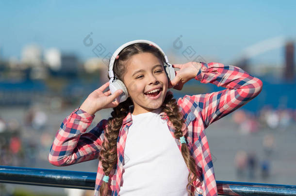 唱快乐。快乐的孩子戴着耳机。小乐迷。快乐的小女孩。小女孩在户外听音乐。<strong>好好享受</strong>吧