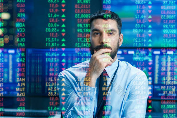 股票市场顶级交易者<strong>着眼</strong>于预测的股票代号和图表运行, 分析数据, 以使最佳销售。在他身后的房间充满了屏幕和统计信息.