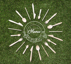 顶部的木勺子的顶部视图与叉子和刀形状的太阳躺在草地上, 菜单题词