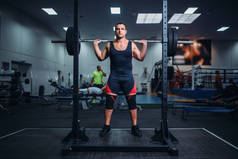 肌肉发达的运动员准备在健身房里用杠铃做蹲。举重锻炼、举重训练
