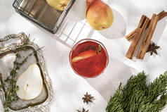 辛辣的红葡萄酒, 肉桂, 八角和切片梨在白色的桌子上的玻璃与成分