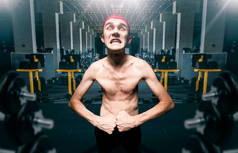 瘦家伙在健身房锻炼时摆姿势, 瘦身营养不良显示肌肉在体育俱乐部, 有趣的健美运动员