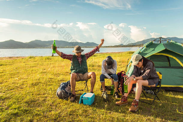 醉酒的游客在草地野营和野餐时聚会。山和湖<strong>背景</strong>。人和生活方式的概念。户外活动和休闲<strong>主题</strong>。背包客和徒步者<strong>主题</strong>