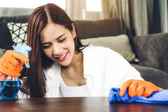 年轻女子戴防护手套, 在家里的客厅里清洗家. 家务和家庭清洁的概念