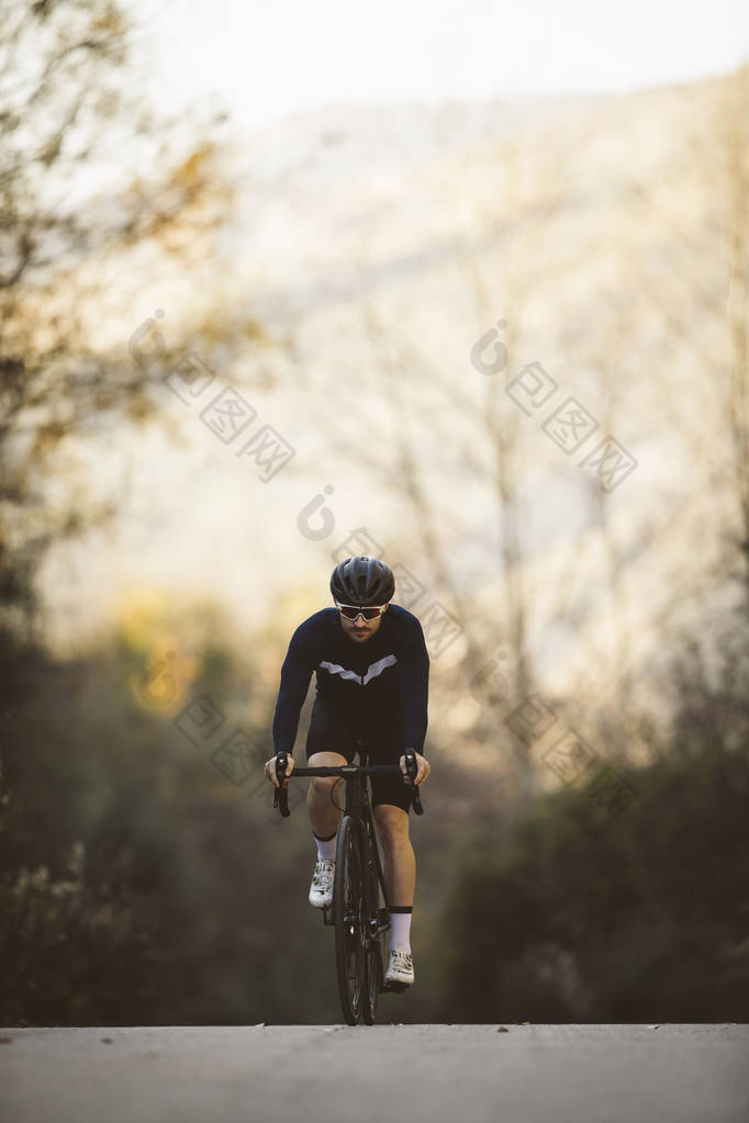 专业的公路自行车赛车手在行动。男子骑自行车山地公路自行车在日落.