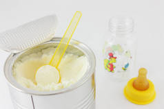 手用勺子在罐与干燥的婴儿奶在白色背景