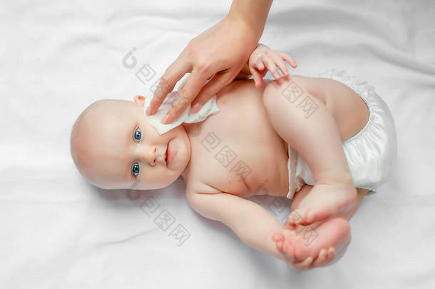 卫生-年轻妈妈在白色背景上用湿巾擦拭婴儿的皮肤、身体和脸部。概念清洁擦拭，净化，清洁.