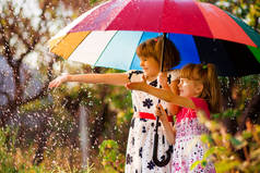 孩子们带着五颜六色的伞在秋雨中玩耍。由于下雨, 小女孩们在公园里玩耍。秋季户外的乐趣为儿童.